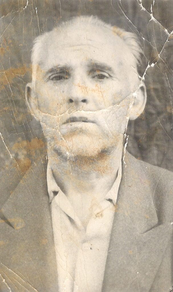 an older Iranian man in a worn suit.